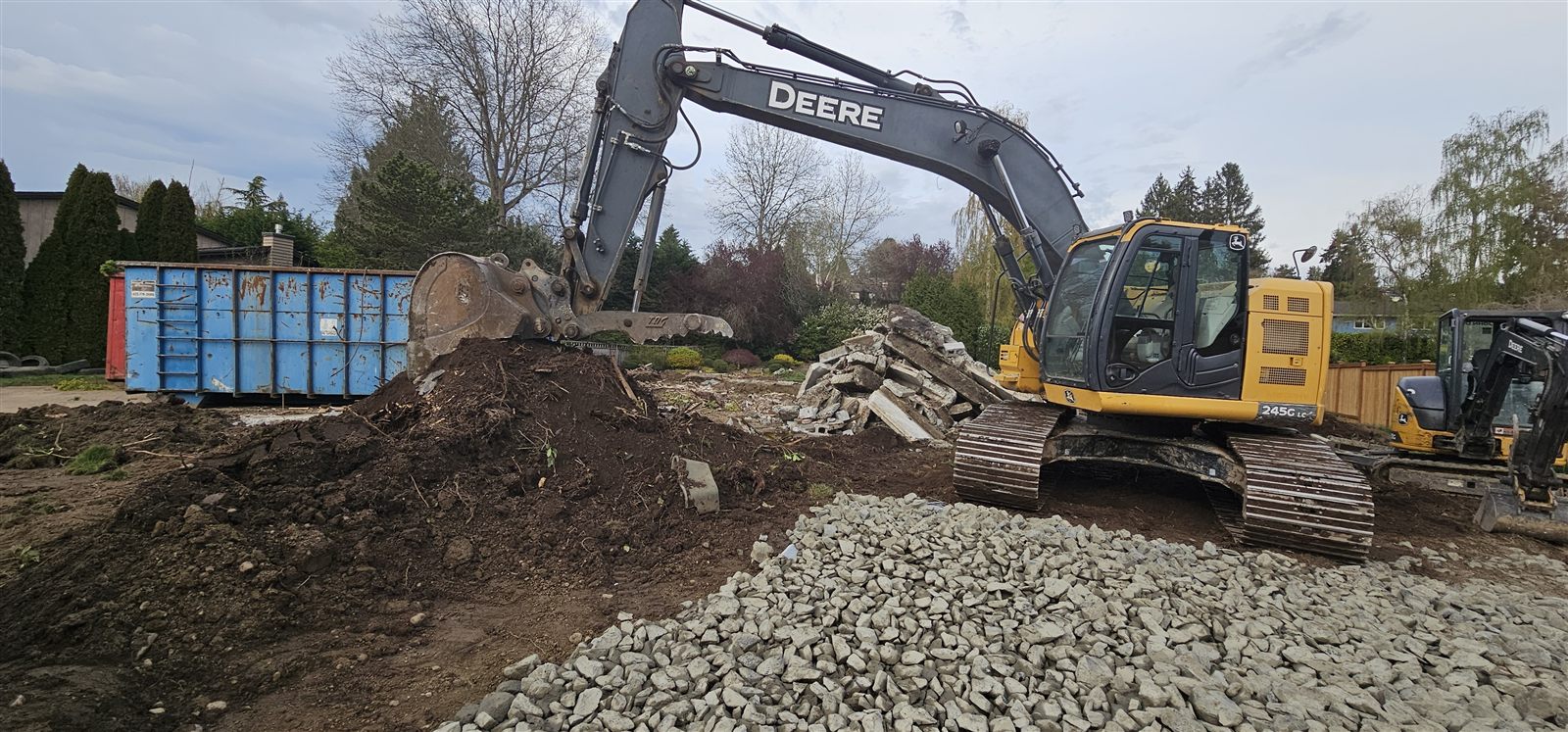 Excavator finish-grading a gravel pad